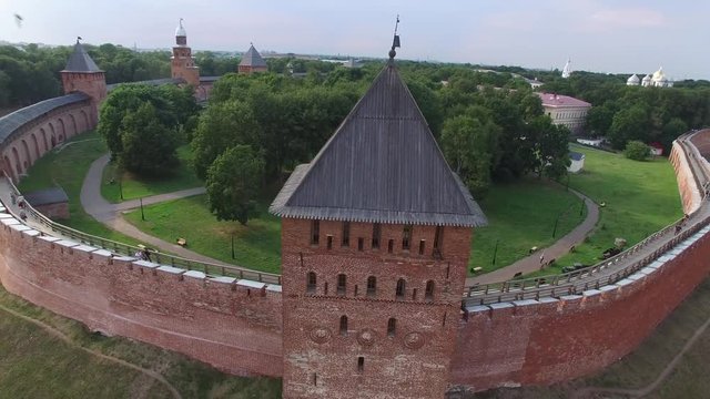 Unique aerial flight around. Veliky Novgorod Kremlin Detinets brick wall. Ancient oldest historical Russian capital. Fortress bank Volkhov River. Drone footage from above. Sunset warm.