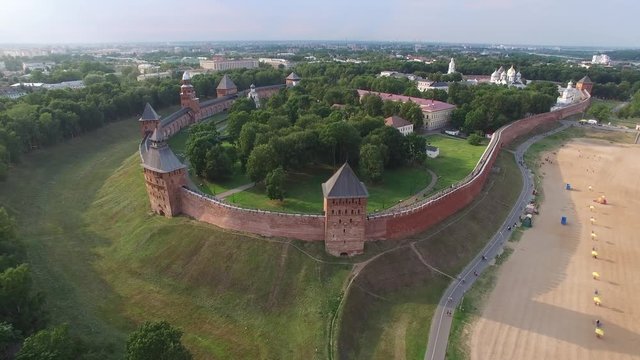 Unique aerial flight above drift Veliky Novgorod Kremlin Detinets historical wall. Ancient oldest Russian capital. Fortress bank Volkhov River. Drone footage from above. Sunset warm light.