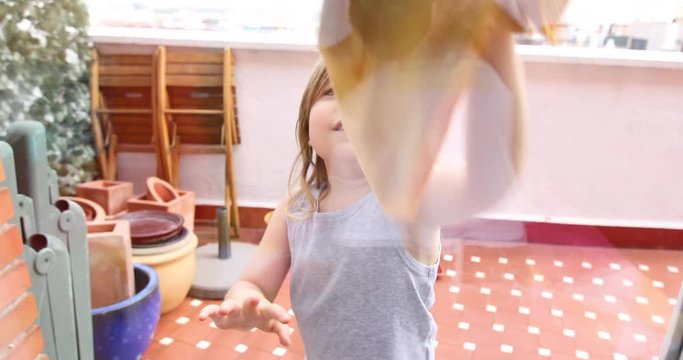 4k video. Front view of three years old child on terrace cleaning glass with rag
