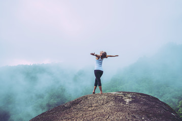 Obraz premium Asian women travel relax in the holiday. Stand on a rocky cliff. Wild nature wood on the mountain.