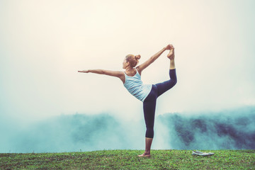 Asian women relax in the holiday. Play if yoga. On the lawn mountain nature