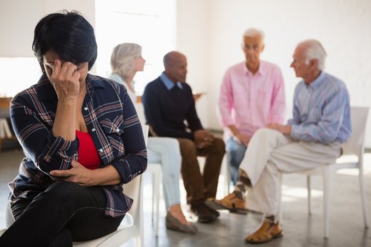 Worried senior woman with friends in background