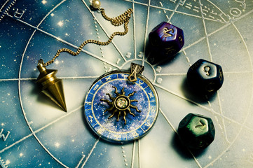 pendulum, astrology dice, zodiac ring with sun over a horoscope