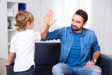 handsome young father giving a high five to his little son