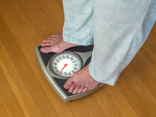 Woman in pajamas weighing herself