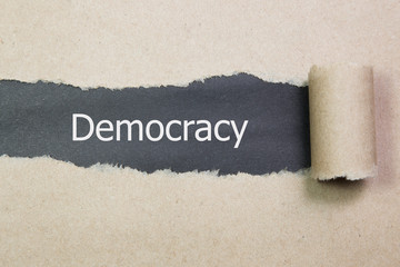 Democracy word written under torn paper.