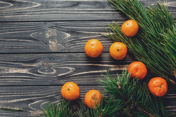 christmas image flat lay. green fir branches with tangerine on rustic wooden background top view. eco design. xmas seasonal greetings. space for text. winter holidays