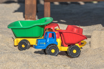 Dump trucks (children's toys) are standing in the sand on the children's playground