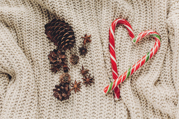 christmas candy and cozy sweater with anise and pine cones on rustic background top view, space for...