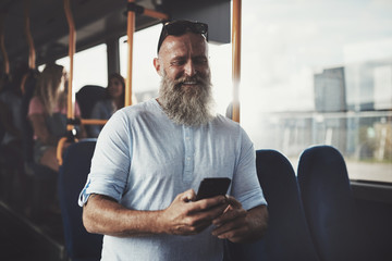 Mature man with a beard using his cellphone on the bus