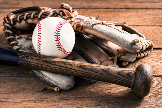 worn out baseball equipment on old wood, ( ball, baseball bat and glove )