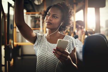 Young African woman riding on a bus listening to music - Powered by Adobe