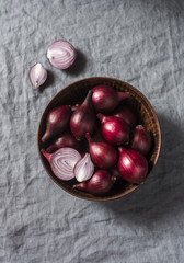 Red onions in a ceramic bowl on a gray background, top view. Spanish onion