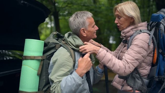 Pleasant aged couple of tourists getting ready fot trip in the forest
