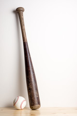 still life photography : used baseball equipment on wood floor against space of bright wall