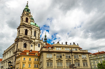 Fototapeta na wymiar Baroque church of St. Nicholas in Malá Strana quarter in the romantic Prague under blue sky. Panoramic of the old city of the hundred towers on a summer day in the capital of the Czech Republic. 
