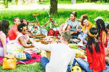 Group of friends enjoying a picnic while eating and drinking red wine