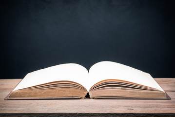 still life photography : opening old book on old wooden table against art dark background