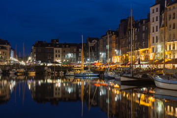 Harbor Honfleur at night with ships and restaurants, France
