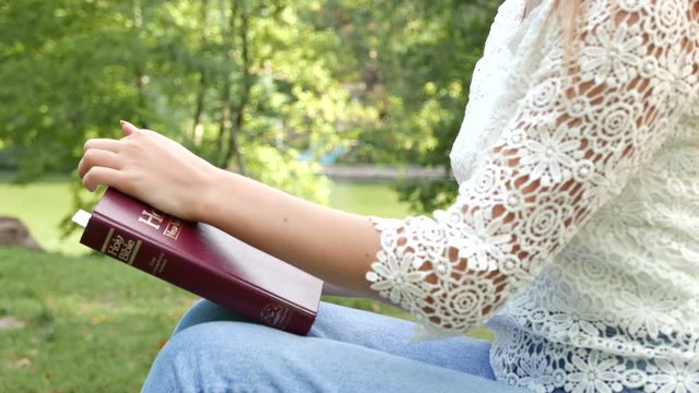 4k.  Body of girl outdoor with Bible. Study Christianity, prayer