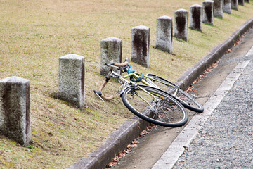 Lying bike on the roadside with bollards. Abandoned bicycle in the park on the way.