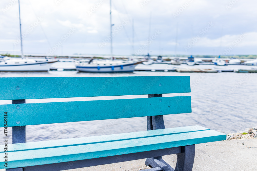 Wall mural empty blue bench overlooking st lawrence river in quebec, canada during summer with boats in harbor