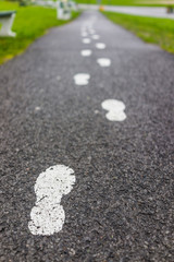 Painted white footprints on asphalt road path as guide