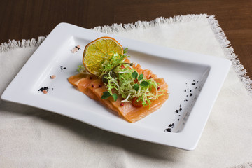 Thin pieces of salted salmon under the greens with the oranges