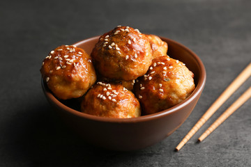 Bowl with delicious meatballs and chopsticks on table