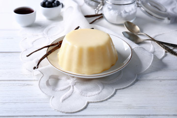 Plate with delicious vanilla pudding on wooden table