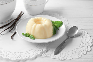 Plate with delicious vanilla pudding on wooden table