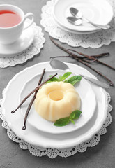 Plate with delicious vanilla pudding on table