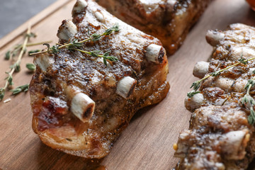 Wooden board with grilled ribs, closeup