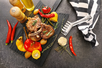 Wooden board with grilled meat on table
