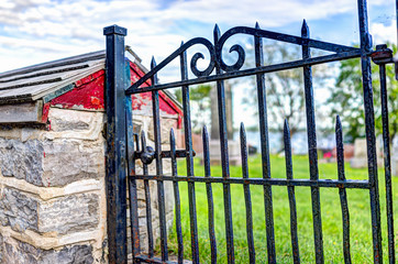 Closeup of small red metal gate to cemetary by church in summer in Europe