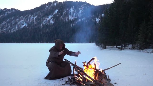 Monk franciscans are warming near fire in winter. Slowmotion 240FPS
