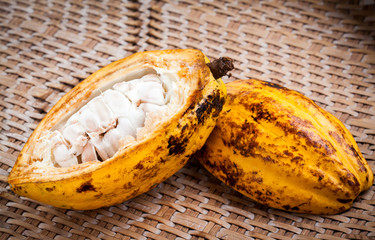 Cocoa beans and cocoa pod on a wooden surface.