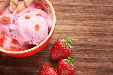 Bowl with delicious strawberry ice-cream on wooden background