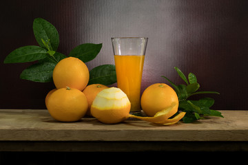 Orange juice and orange peel off on wooden table in dim light night.Still life style and selective...