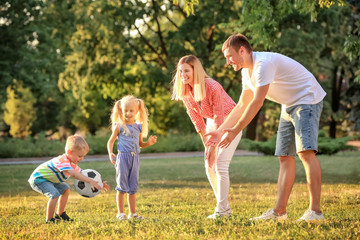 Naklejka na ściany i meble Happy family playing football in park on sunny day