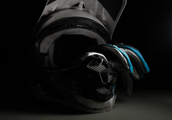 Motocross helmet and gloves. Dirty motocross helmet. Moto equipment. Conceptual photograph of a...