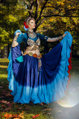tribal dancer in a blue dress on a background of trees