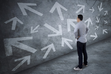 Confused young man looking at arrows