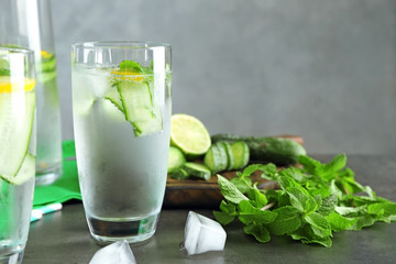 Glass of fresh cucumber water with lemon and mint on table