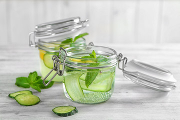 Jars of fresh cucumber water with lemon and mint on table