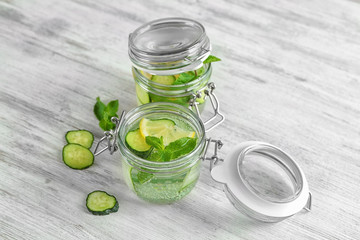 Jars of fresh cucumber water with lemon and mint on table