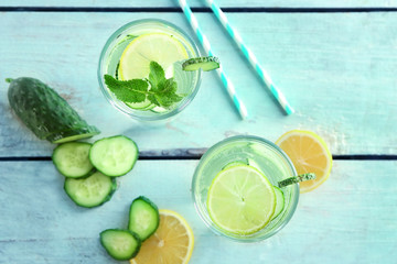 Glasses of fresh cucumber water with citrus fruits and mint on table