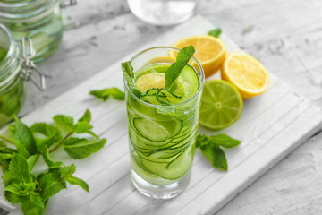 Glass of fresh cucumber water with lemon and mint on table