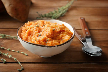 Bowl with mashed sweet potato on wooden background