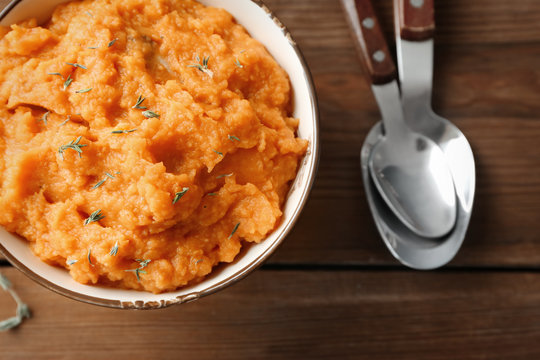 Bowl with mashed sweet potato on wooden background